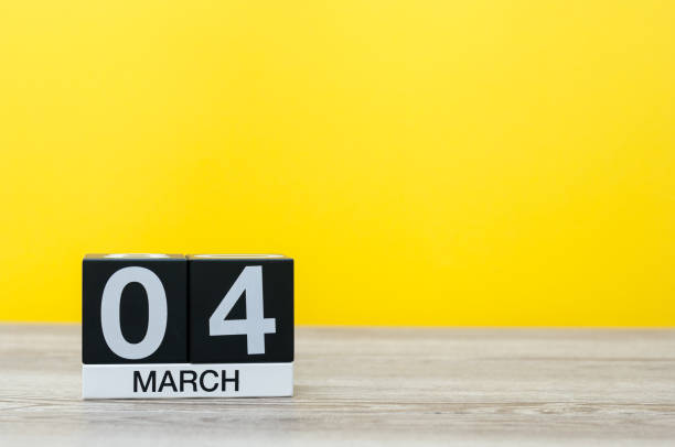 istock March 4th. Day 4 of month, calendar on table with yellow background. Spring time, empty space for text 925103808