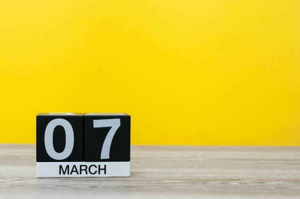 istock March 7th. Day 7 of month, calendar on table with yellow background. Spring day, empty space for text 925103822