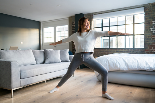 Fit woman exercising at home stretching and looking very happy - lifestyle concepts