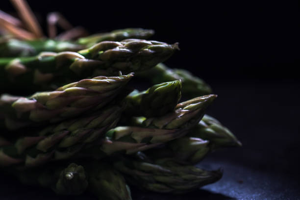 Macro on a bunch of tied up green asparagus, very dark