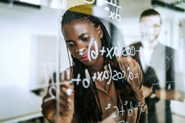 Writing Mathematical Formulas On Transparent Wipe Board Colleagues Writing Mathematical Formulas On Transparent Wipe Board math teacher stock pictures, royalty-free photos & images