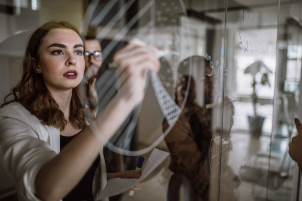 There must be a solution! Colleagues Writing Mathematical Formulas On Transparent Wipe Board writing on chalk board stock pictures, royalty-free photos & images
