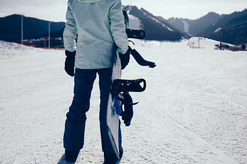 snowboarder with snowboard on ski piste in winter mountains