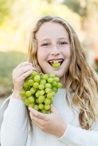 Young girl eating grapes.