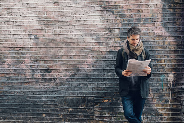 jeune homme lisant les journaux lors du bris - reading newspaper men magazine photos et images de collection