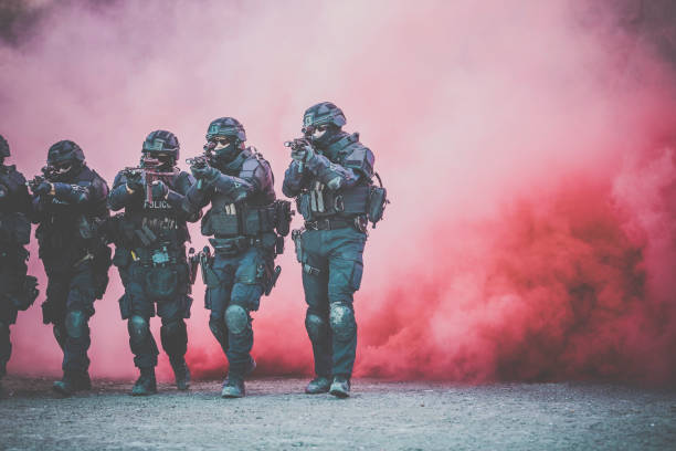 Swat Police Officers Shooting With Firearm Swat Police Officers Shooting With Firearm while crossing a red smoke wall target shooting photos stock pictures, royalty-free photos & images