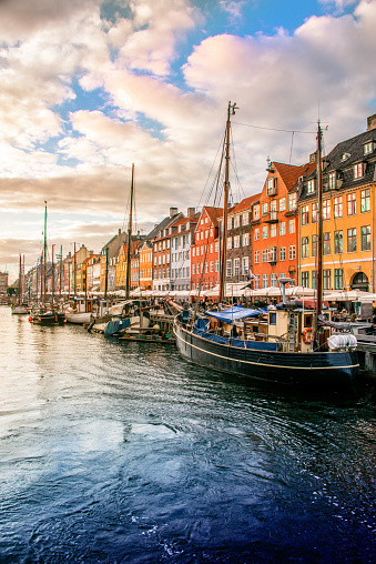 Beautiful sunrise over canal in Copenhagen, Denmark; colorful buildings, sky and boats reflect in calm water