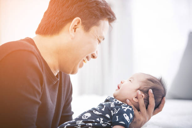 Proud father holding his newborn baby son in his at home. stock photo