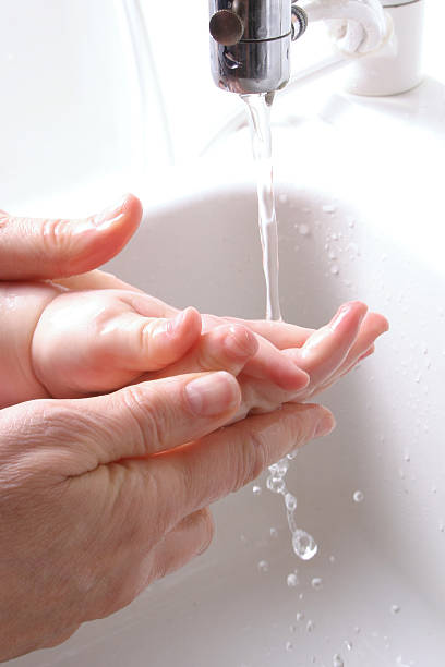 Washing hands of a baby at the sink stock photo