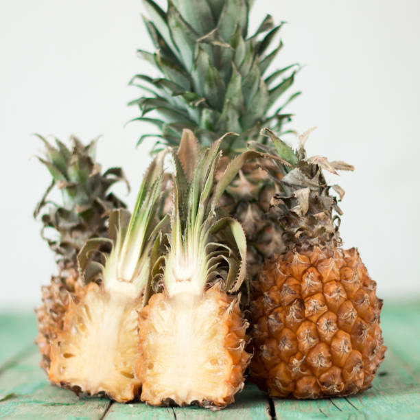 Ripe pineapple and baby pineapple on a wooden background, tropical fruits