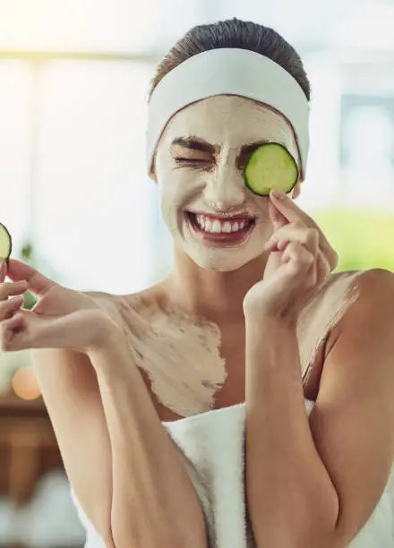 Shot of an attractive young woman holding cucumber slices in front of her eyes
