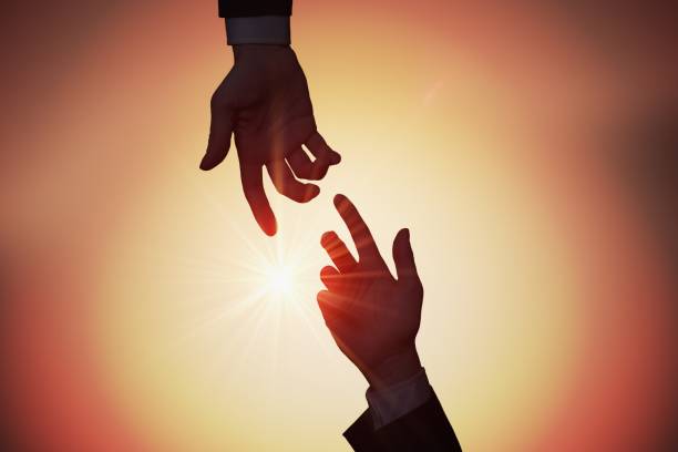 istock Help and assistance concept. Two hands are reaching each other at sunset. 925159278