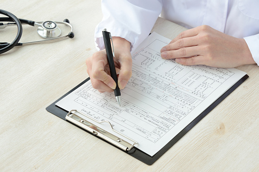 Medical scene, doctor writing on medical record