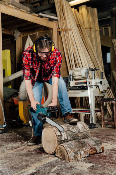 istock joiner in the workshop saws the tree with an electric chainsaw. carpenter in the process of sawing 925163832
