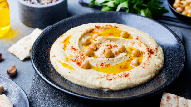 Hummus, chickpea dip, with spices and pita, flat bread in a black plate on grey stone background. Top view. Hummus, chickpea dip, with spices and pita, flat bread in a black plate on grey stone background. Top view sumac stock pictures, royalty-free photos & images