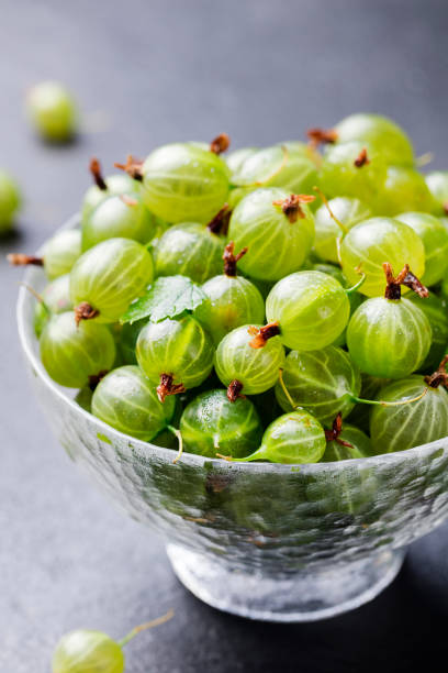 istock Gooseberries in glass bowl on black stone slate background. 925167024