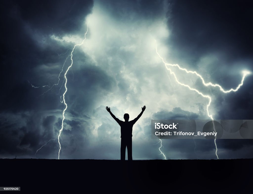 A man silhouette on a storm background. A man silhouette on a storm background. Lord of the lightning. Background on the theme of survival, religion, philosophy, psychology. Lightning Stock Photo