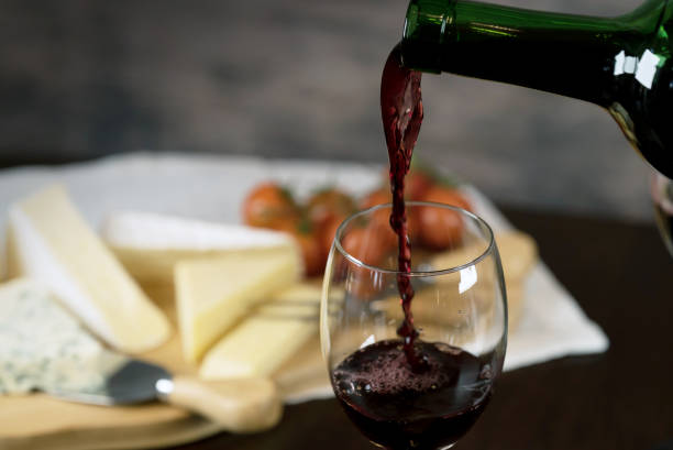 istock Red wine poured into a glass with cheese board 925176354