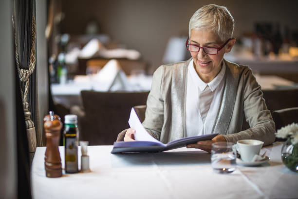 istock Happy mature woman reading Menu in a restaurant. 925179224