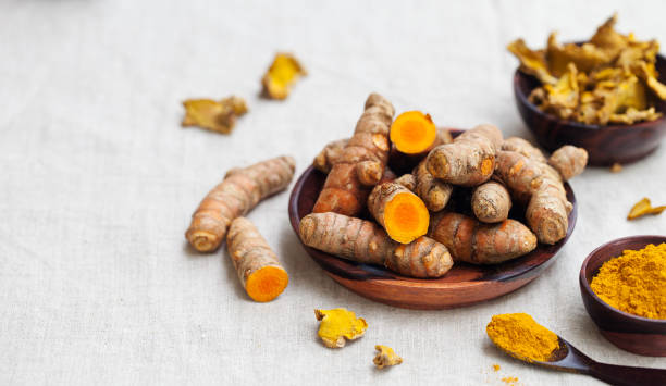istock Fresh and dried turmeric roots in a wooden bowl. Grey textile background. Copy space. 925179708