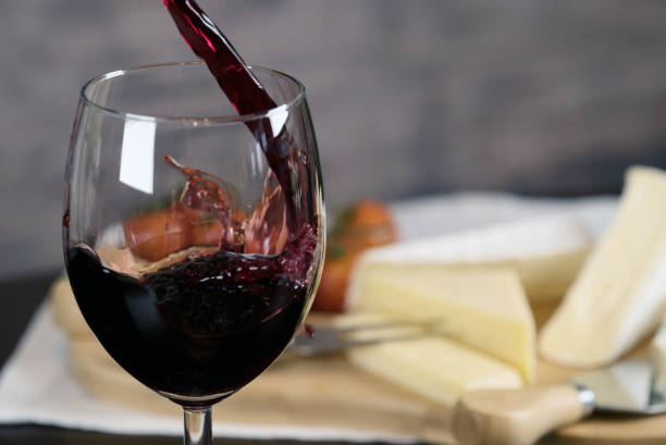 istock Red wine poured into a glass with cheese board 925183236
