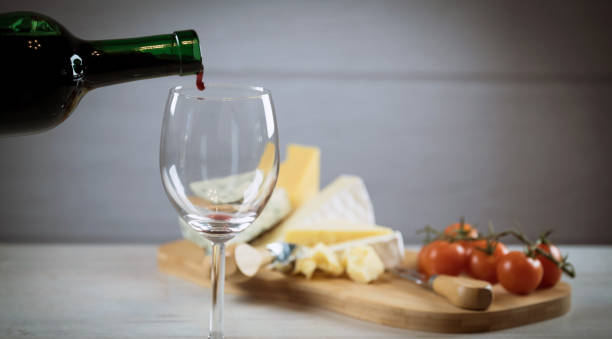 istock Red wine poured into a glass with cheese board 925183256