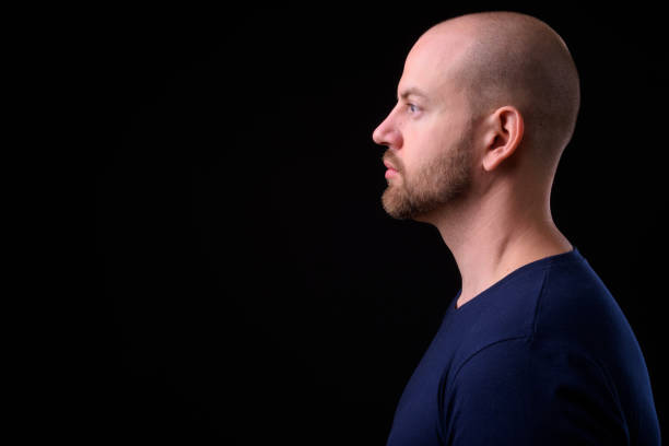 istock Young handsome bearded bald man with tattoos against black background 925183906
