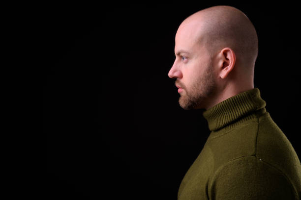 istock Young handsome bearded bald man with tattoos against black background 925184530