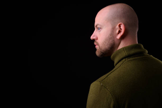 istock Young handsome bearded bald man with tattoos against black background 925184550