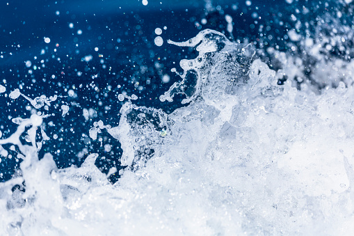 Splashing sea water with foam, bubbles and defocused lights. Close up detail of the wake of large cruise ship.