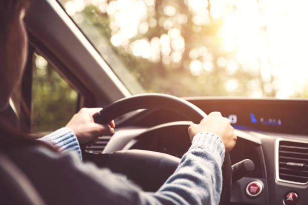 donna alla guida dell'auto al sole. - steering wheel foto e immagini stock