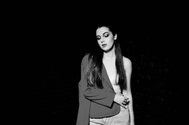 istock Stylish brunette girl on red jacket against studio black brick wall. 925192998