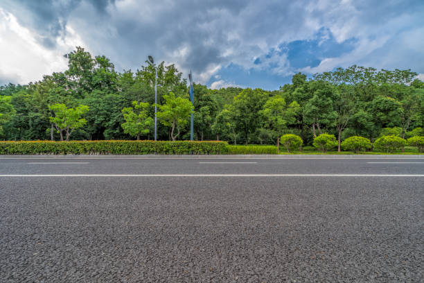 istock Asphalt road and green trees under blue sky 925194040