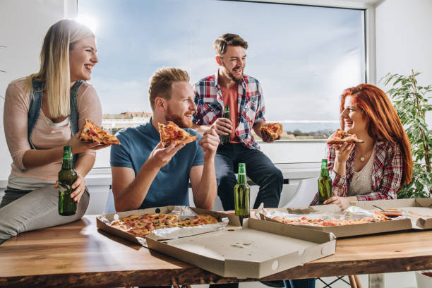 istock Happy friends talking while eating pizza for lunch at home. 925202702