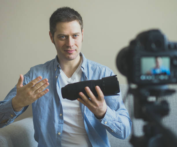 istock Handsome man making video blog about photo camera lenses. 925207902