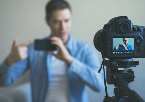 istock Man making video blog about mobile phones. Focus on camera. 925207906