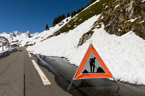 Warning sign because of a road blocked by a snow slide in the Alps