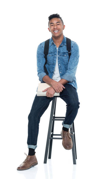 przystojny młody mężczyzna student siedzący na stołku i trzymający książki - sitting young men book isolated on white zdjęcia i obrazy z banku zdjęć