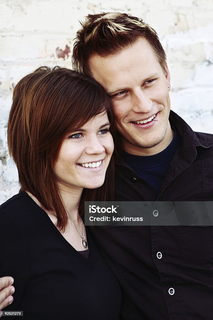 Felice giovane coppia contro il muro di mattoni - Foto stock royalty-free di Abbigliamento casual