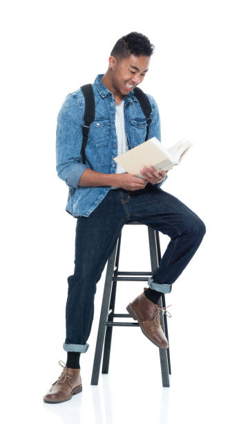 istock Handsome young male student sitting on stool and holding books 925215236