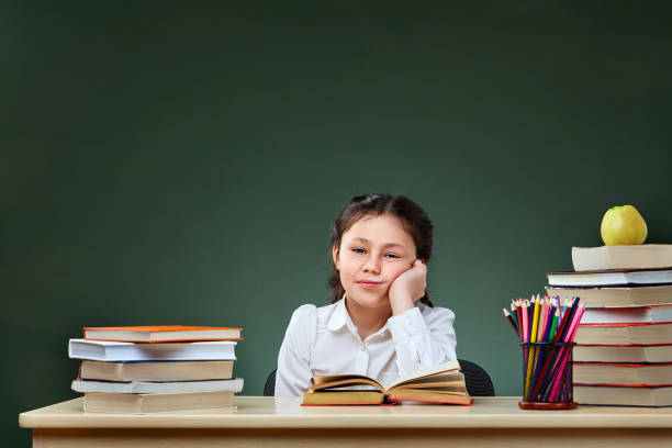istock Girl with books points on green chalkboard 925218408