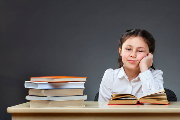 istock Cute industrious child is sitting at a desk indoors. Kid is learning in class on background of blackboard. 925219574