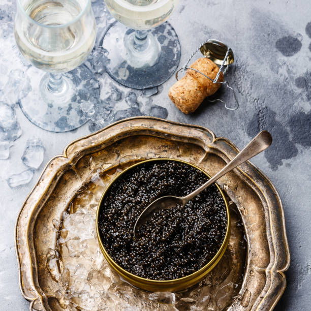 istock Black caviar in can on ice and champagne 925222492