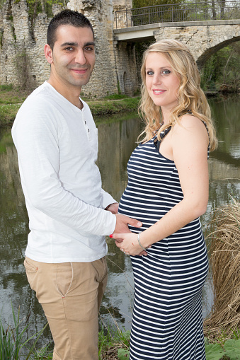 happy pregnant woman with husband married couple in the Park