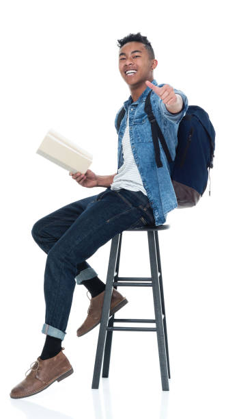 istock Handsome young male student sitting on stool and holding books 925223924