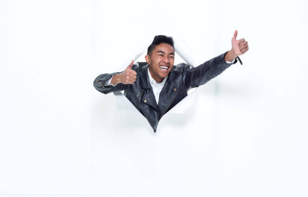 istock Good looking young man bursting through a tear in paper 925224370