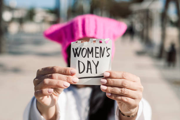 istock woman with a pink hat and the text womens day 925224580