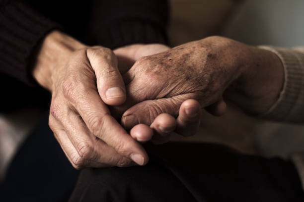 young man holding the hand of an old woman closeup of a young caucasian man holding the hand of an old caucasian woman with affection alzheimers disease photos stock pictures, royalty-free photos & images