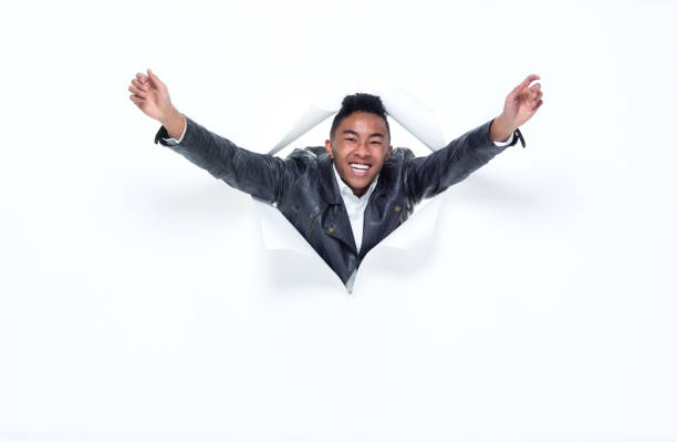 istock Good looking young man bursting through a tear in paper 925226494