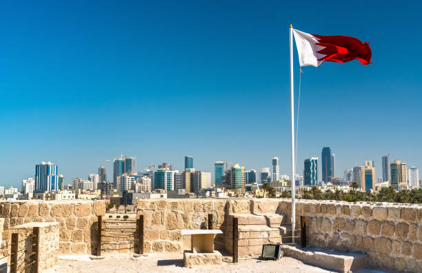 bandiera del bahrain con skyline di manama al forte del bahrain. patrimonio mondiale dell'unesco - bahrain foto e immagini stock